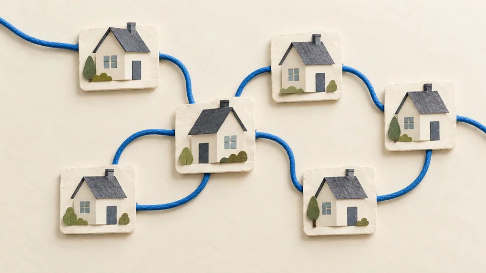 Small paper house models linked by a looping blue cord.